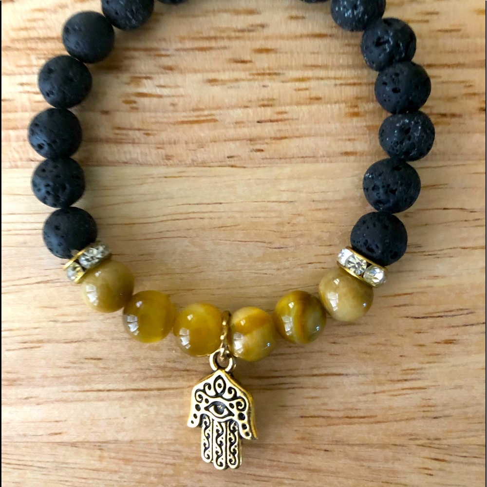 Hamsa hand charm on lava stone beads bracelet with brownish beads or stones.